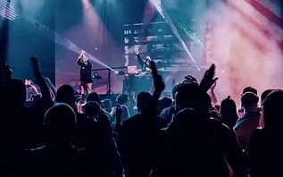 Iilots of people in a crowd attending an open air music event with singers on a stage at night. , at events when you visit langebaan