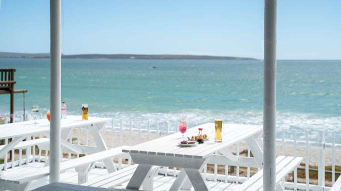 Great views and sunset on white deck with table and chairs at Langebaan Restaurants
