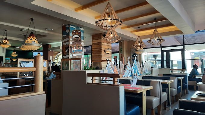 Interior of San Luis Spur as one of the Langebaan Restaurants in Malls, with wooden finish, light fittings , tables and seating.