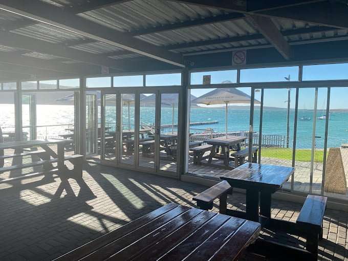 The view at Friday Island on the lagoon through glass windows. Inside tables and chaiers. Outside grass and lagoon.