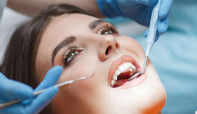 Iipatient for a check up at a dentist in langebaan with mouth wide open with instruments in her mouth