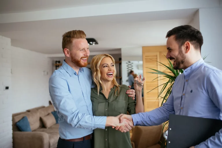 Iia young couple in their new home are being congratulated by the estate agent , with the shake of hands, after buying property in langebaan successfully.