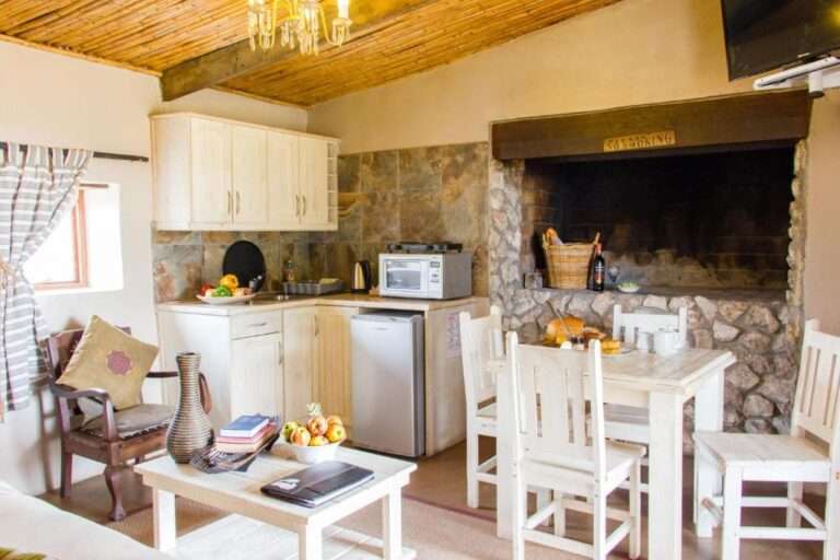 Love weskus ilove weskus ithe kitchen of the chalets at thali thali game lodge showing kitchen table, chairs, fireplace and kitchenette