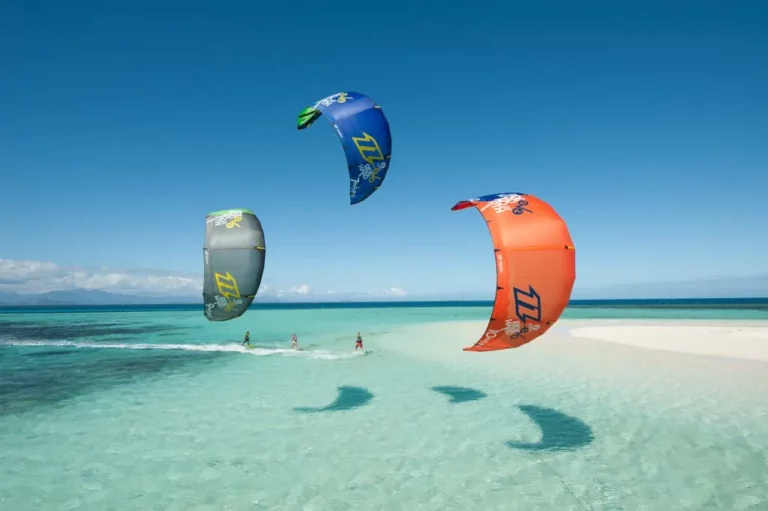 Iikite surfing on the langebaan lagoon with crystal clear water emphasis langebaan as a water sports paradise with 3 kite surfers sailing on the water.