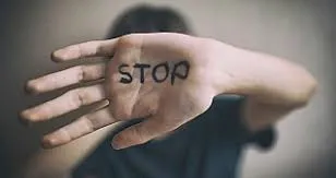 Iia hand with the words "stop" written on it and cover its face, symbolizing stop the abuse.
