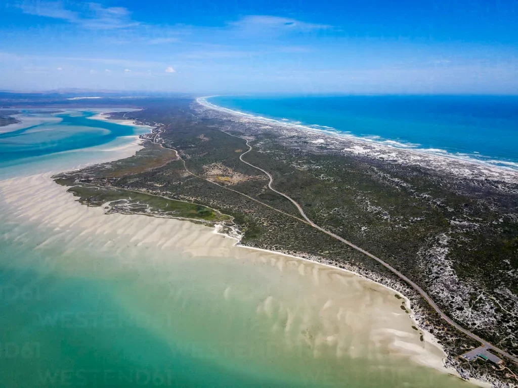 Iithe view of the langebaan lagoon on the one side and atlantic ocean on the other side, showing land and sea and beach from a distance