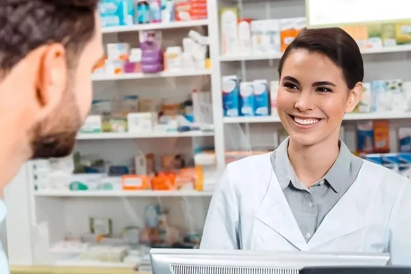 Iiassistant provide medicine to customer over the counter with a smile at a pharmacy in langebaan.