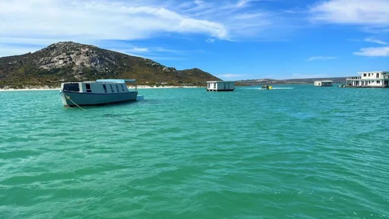 Iithis picture shows the langebaan lagoon at kraalbaai with the different boat houses in langebaan, all over the bay and the hill top in the background
