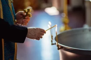 Love weskus ilove weskus ia priest lights up a candle during a church service in langebaan, holding onto a cross in his hand