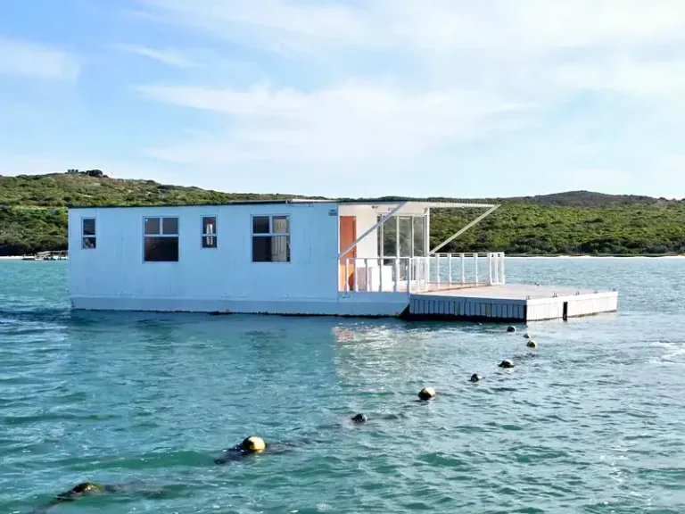 Iiharmony boat house from the sea with flat lagoon waters around it.