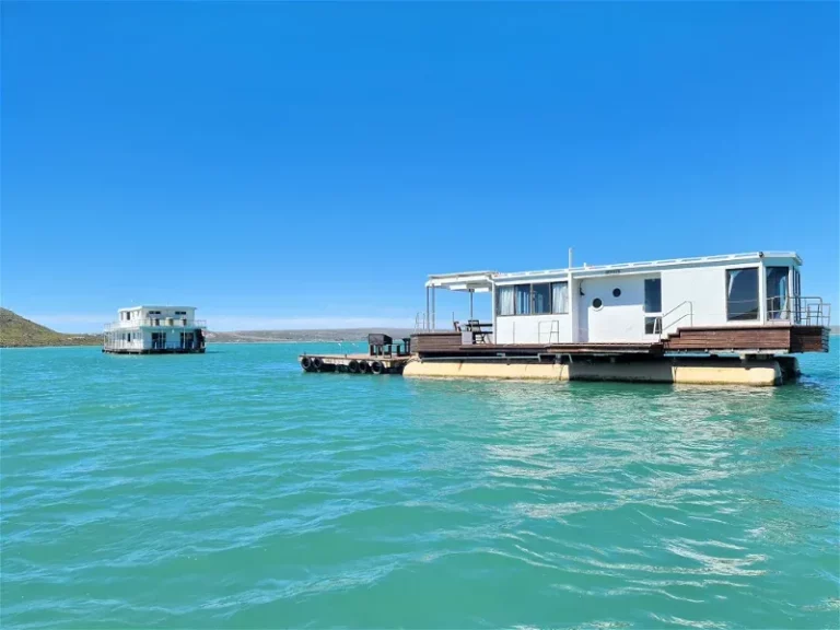 Iia view from the water towards the larus house boat in langebaan showing the length and floating deck with other house boat in a distance.