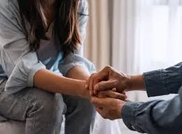Iia professional gives support to a girl with trauma on a couch.