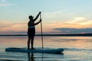 Iia man enjoys sup at sunset on the langebaan lagoon