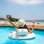 Iigirl relaxes in a swimming pool with a cocktail enjoying the view over the langebaan lagoon after finding langebaan accommodation accommodation for your great staycation. Variety options available for all budgets.