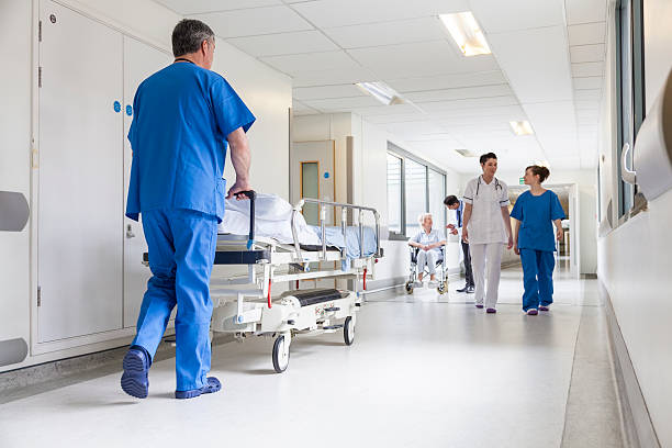 Iithe interior of a hospital with a patient being pushed on hospital bed and medical staff walking in the passage. All providing professional medical care at hospitals with medical assistance and services in langebaan