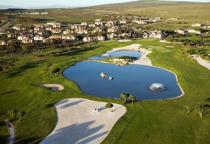 Love weskus ilove weskus iaerial view of a golf course with two large ponds, white sand bunkers, and a town in the background at the langebaan country estate in langebaan