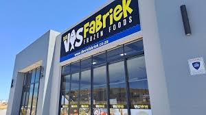 Exterior of a frozen foods store with a blue and yellow sign, large glass entrance, and clear sky above.