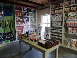 Interior of a shop with wall shelves stocked with colorful products and a wooden table in the center displaying baskets of items.