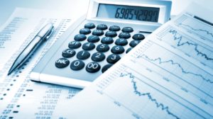 Calculator on a desk beside financial graphs and charts, suggesting financial analysis of data.