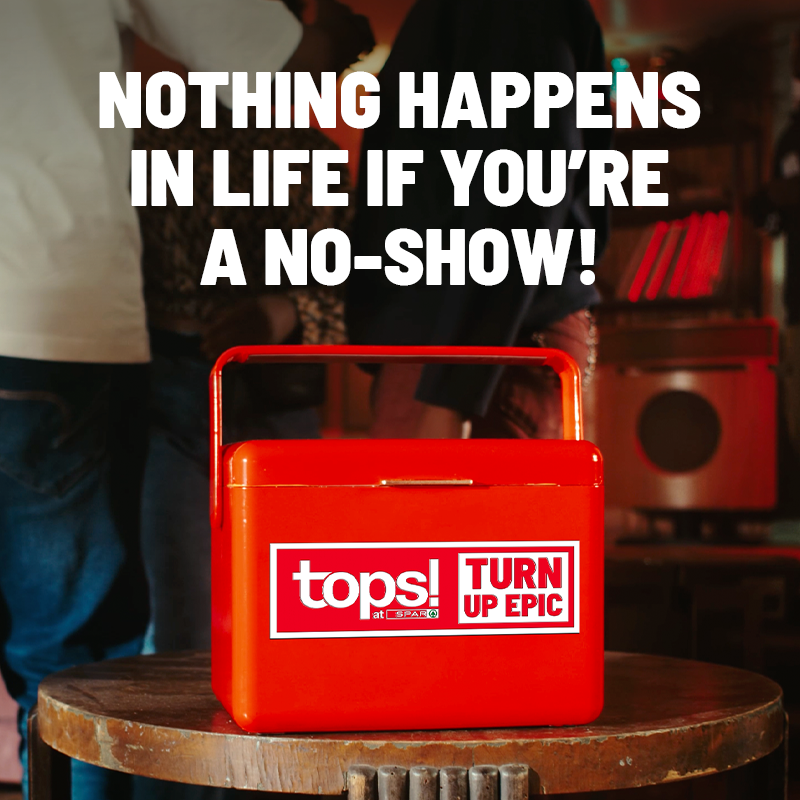 Red cooler with Tops! branding sits on a round wooden table in a bar setting, overlaid with bold white slogan: "NOTHING HAPPENS IN LIFE IF YOU'RE A NO-SHOW!"