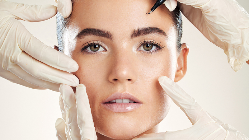 Aesthetics treatments – – Iiclose-up of a woman receiving a cosmetic facial treatment with gloved hands on her face.